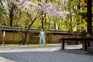 a woman standing in front of a tree with purple flowers at Miya Townhouse by Reflections in Kyoto