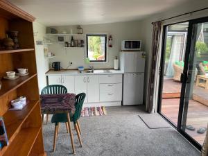 a kitchen with a refrigerator and a table and a chair at Beach Bach Whangaumu Bay Tutukaka in Tutukaka