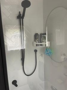 a shower with a black shower head in a bathroom at Beach Bach Whangaumu Bay Tutukaka in Tutukaka +21 photos