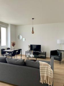 a living room with a grey couch and a tv at Au Petit Colombage - Cosy au centre de Mulhouse - Gare proche in Mulhouse