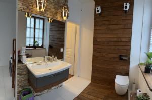 a bathroom with a white sink and a wooden wall at Dako Apartment, Luxurious, Cosy, Spacious in Rzeszów