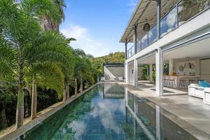 an infinity pool in the backyard of a house with palm trees at Villa Ti Karibu in Les Trois-Îlets
