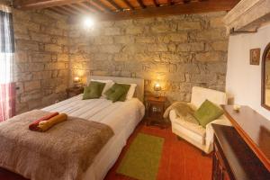 a bedroom with a bed and a chair and a stone wall at Entre a Pedra e o Mar in Faial da Terra