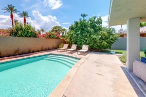 a swimming pool with two chairs next to a house at Desert Retreat in Indian Wells