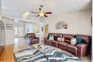 a living room with a leather couch and a ceiling fan at Evening Star in Indian Wells