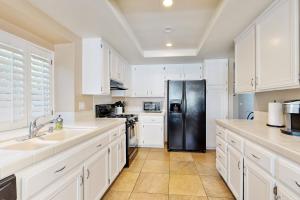 a kitchen with white cabinets and a black refrigerator at Evening Star in Indian Wells +17 photos