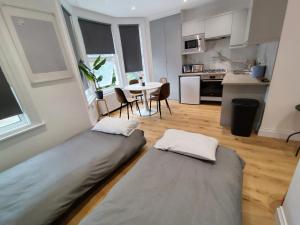 two beds in a room with a kitchen and a table at Best in Class - London, Harrow in Harrow