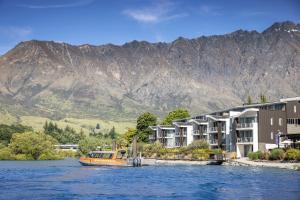 a boat on the water in front of buildings and mountains at Hilton Queenstown Resort & Spa in Queenstown