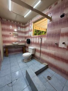 a pink tiled bathroom with a toilet and a window at TerraZica hostal in Brisas de Zicatela