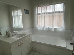 a bathroom with a tub and a sink and a mirror at Stunning Mount beachside location in Mount Maunganui