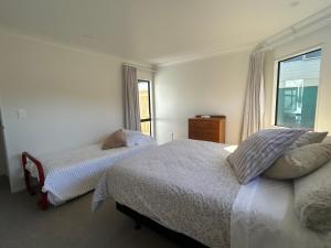 a bedroom with two beds and a window at Stunning Mount beachside location in Mount Maunganui