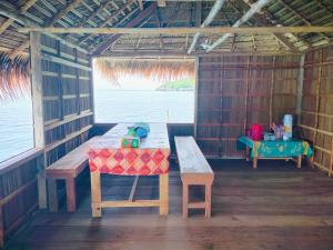 a table and bench in a hut with a view of the ocean at Kafdarun Homestay in Dokkor