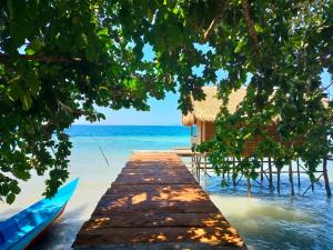 a dock on the beach with a house and the ocean at Kafdarun Homestay in Dokkor +20 photos