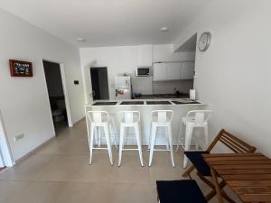 a kitchen with a white counter and white stools at Apartamento en tigre in Tigre