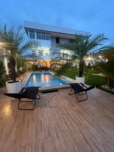 a swimming pool with two chairs in front of a building at Cevero Rodriguez Hotel Boutique in Yurimaguas