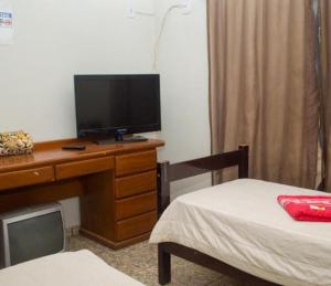 a room with a desk with a television and a bed at Hotel Pousada na Br 040 in Valparaíso de Goiás +17 photos