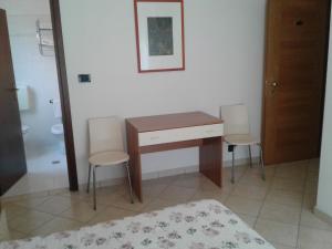 塔比亞諾的住宿－Albergo Moderna，一间卧室配有书桌、两把椅子和一张床