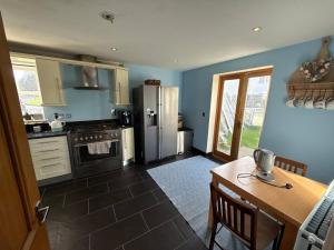 a kitchen with a refrigerator and a table in it at Silsoe Cottage BB Master Suite in Bedford