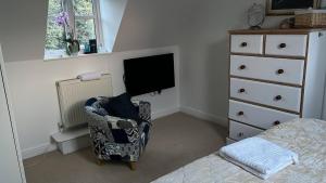 a bedroom with a bed and a tv and a chair at Silsoe Cottage BB Master Suite in Bedford