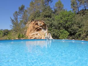 a swimming pool with a water fall in front of a mountain at Orchidée in Barjols