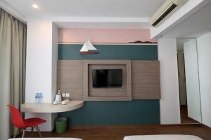 a living room with a tv and a red chair at DK Belstar Hotel Belitung in Tanjungpandan
