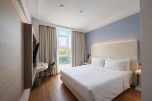 a bedroom with a white bed and a desk and a window at DK Belstar Hotel Belitung in Tanjungpandan