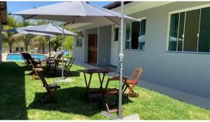 a patio with a table and chairs and an umbrella at chácara vale do sol in Valença