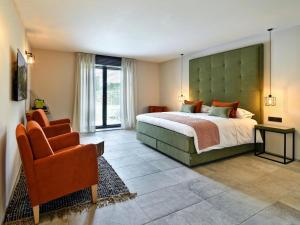 a bedroom with a large bed and a chair at Villa with Pool & Suites for 12 Guests in Durbuy