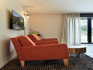 a living room with a orange couch and a table at Villa with Pool & Suites for 12 Guests in Durbuy
