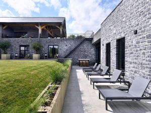 a row of chaise lounges on a patio next to a building at Villa with Pool & Suites for 12 Guests in Durbuy