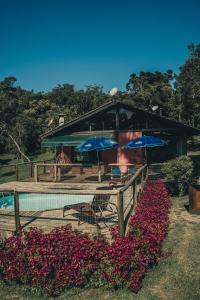 a building with umbrellas and flowers next to a pool at Chacara da Dinda in Piraquara