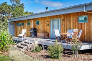 a house with a deck with a table and chairs at Bruny Island Escapes and Hotel Bruny in Alonnah