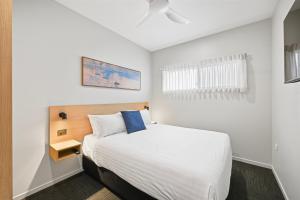 a bedroom with a white bed with a blue pillow at Avenue WEST Studio Units in Toowoomba