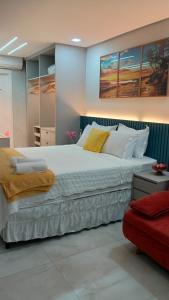 a bedroom with a large white bed with paintings on the wall at Studio Luxuoso frente Mar in Salvador +87 photos