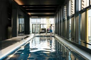 a woman standing next to a swimming pool in a building at Quincy Hotel Melbourne in Melbourne