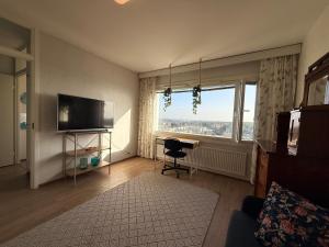 a living room with a television and a desk and a window at The Treetop Apartment in Turku