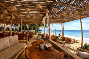 a restaurant on the beach with a couch and a table at HA Beach Breeze in Jambiani