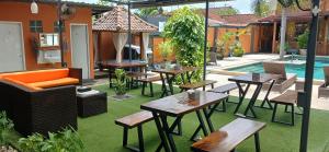 an outdoor patio with tables and chairs and a pool at Dewi Sri Guesthouse in Mataram