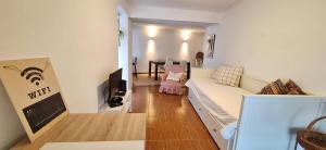 a living room with a white couch and a tv at Daniel in Lagoa