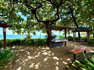 a picnic table and a bench under a tree at Dome by the sea in Trinity Beach