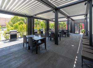 a covered patio with tables and chairs and a grill at HOTEL R9 Kujukuri "ex Casual Resort COFF Ichinomiya" in Ichinomiya