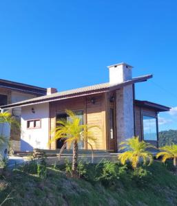 a house with palm trees in front of it at Chalé Recanto do Pimenta 02 in Venda Nova do Imigrante