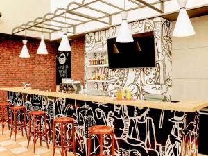 eine Bar mit roten Barhockern und einer schwarz-weißen Wand in der Unterkunft Hotel Ibis Łódź Centrum in Łódź