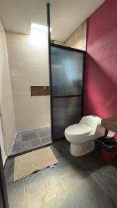 a bathroom with a toilet and a red wall at Cerro Escondido in Chiapa de Corzo