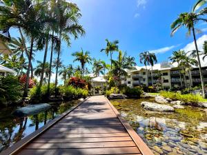 a walkway at a resort with palm trees and a pond at The Beachfront in Trinity Beach