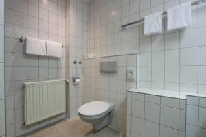 a white tiled bathroom with a toilet and a shower at Arthotel ANA Panorama, Trademark Collection by Wyndham in Marktoberdorf +133 photos