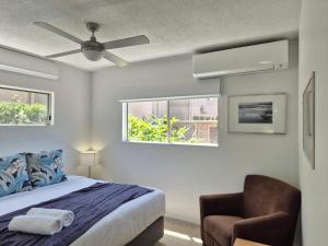 a bedroom with a bed and a chair and two windows at Noosa Sun - On the Noosa River in Noosaville +76 photos