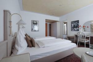 a white bedroom with two beds and a table at Arthotel ANA Panorama, Trademark Collection by Wyndham in Marktoberdorf