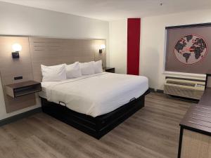 a hotel room with a large bed with white sheets at Ramada by Wyndham Albany GA in Albany
