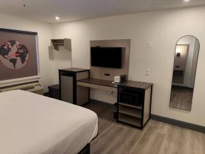 a hotel room with a bed and a desk with a television at Ramada by Wyndham Albany GA in Albany +8 photos